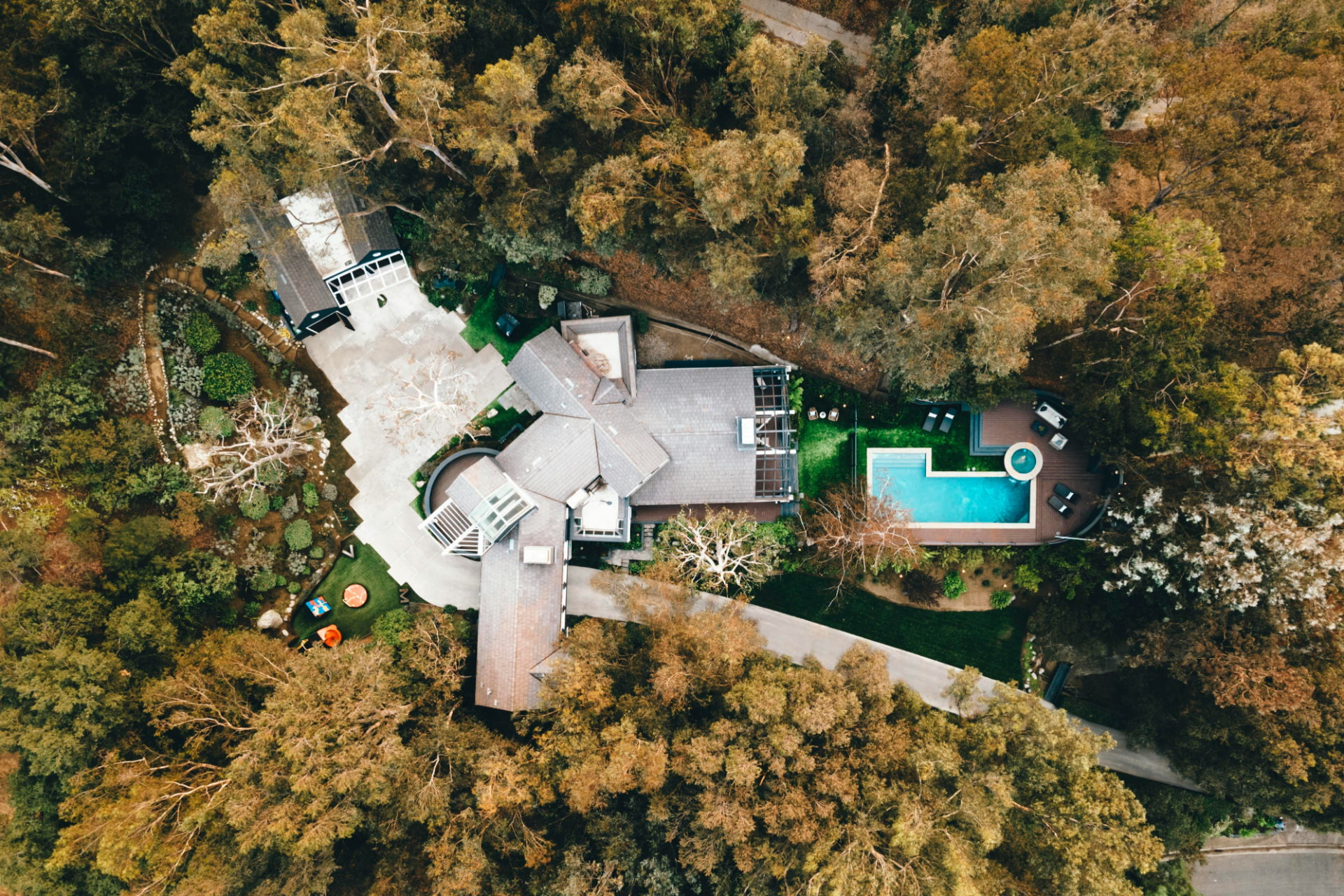 Top-down aerial drone photo of a home with a pool, surrounded by trees